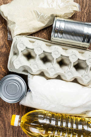 Food delivery Donation, quarantine help concept. Oil, canned food, pasta, bread, sugar, egg. Wooden background. Top viewの写真素材