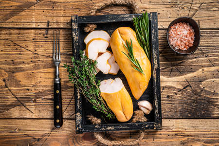 Hot Smoked chicken breast fillet meat on a wooden board with herbs. wooden background. Top viewの写真素材