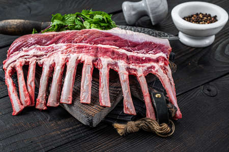 Rack of lamb ready for cooking on a butcher cutting board. Black background. Top viewの写真素材