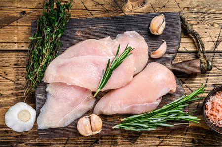 Fresh Raw sliced cut chicken breast fillet steaks on a wooden cutting board with kitchen knife. wooden background. Top viewの写真素材