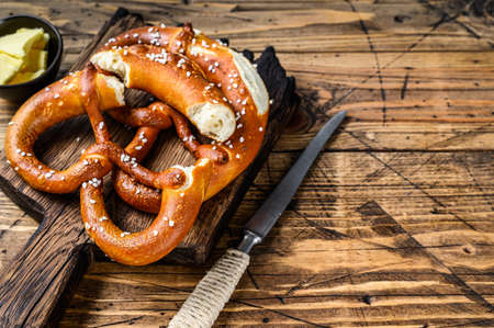 Baked pretzels with sea salt on a rustic wooden cutting board. Wooden background. Top view. Copy...
