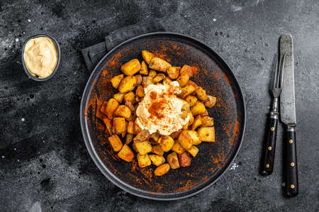 Patatas Bravas, traditional Spanish tapas, baked potato with spicy tomato sauce. Black background. Top viewの写真素材