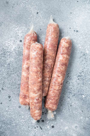 Bratwurst raw sausages on a kitchen table. Gray background. Top view