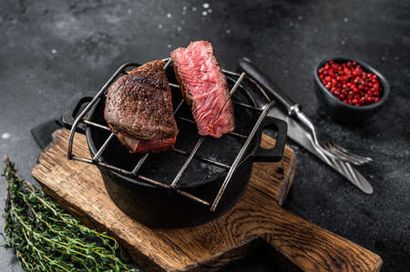 Beef tenderloin steak is grilled on a grill pan. Black background. Top viewの写真素材