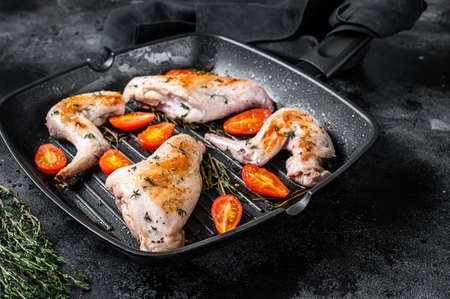 Roasted rabbit legs in a pan with thyme. Black background. Top viewの写真素材