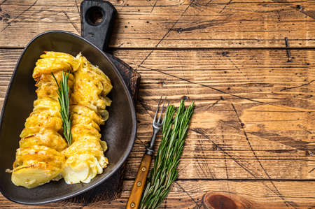 Potato casserole Gratin in a plate with herbs. wooden background. Top View. Copy spaceの写真素材