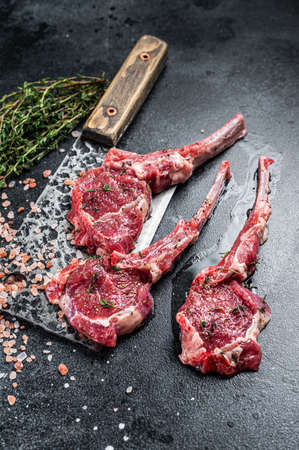 Raw uncooked lamb mutton meat chops steaks on a butcher cleaver. Black background. Top viewの写真素材