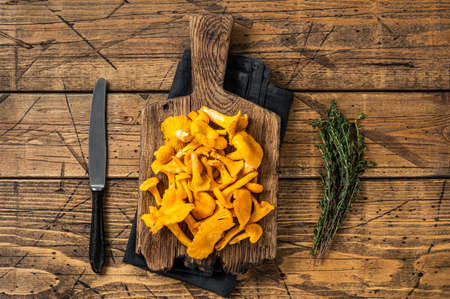 Wild Raw uncooked Chanterelles mushrooms on a cutting board. Wooden background. Top viewの写真素材