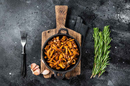 French roasted chanterelle mushrooms with onions and thyme in a pan. Black background. Top viewの写真素材
