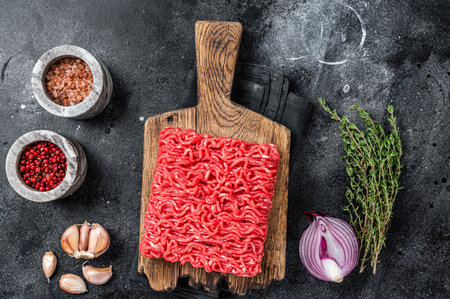 Raw Mince, minced Ground beef meat on a cutting board. Black background. Top view