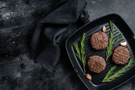Grilled burger meat patties with spices on grill pan. Black background. Top view. Copy space