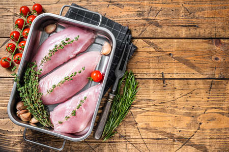 Cooking of Raw Turkey steaks, Breasts fillet with thyme and rosemary. Wooden background. Top view. Copy spaceの写真素材