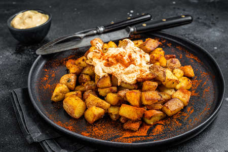 Patatas Bravas, traditional Spanish tapas, baked potato with spicy tomato sauce. Black background. Top viewの写真素材