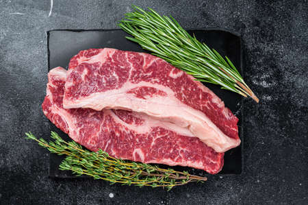 Raw Striploin steak or New York steak beef meat cut. Black background. Top view