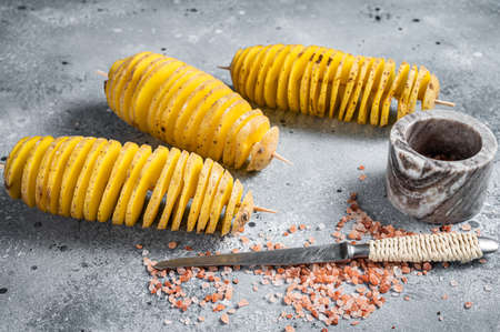 Uncooked raw Tornado or Twist potato fries. Wooden background. Top view. Copy space