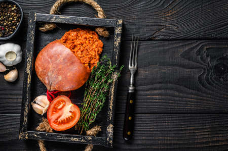 Mallorcan Sobrassada cured pork meat sausage in a wooden tray. Black wooden background. Top view. Copy spaceの写真素材