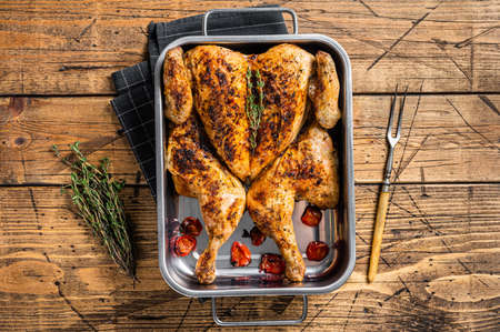 Homemade chicken rotisserie with thyme in baking dish. Wooden background. Top view
