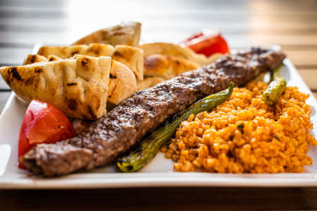 Traditional Turkish Adana kebab or kebap meat food with marinated peppers, bread and rice pilaf. Top...