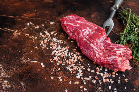 Uncooked Raw flank beef steak on meat fork. Dark background. Top view. Copy spaceの写真素材