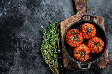 Roasted cherry tomatoes with thyme in a pan. Black background. Top view. Copy spaceの写真素材