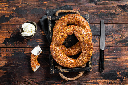 Stack of fresh baked Turkish simit bagel with kaymak. Wooden background. Top view