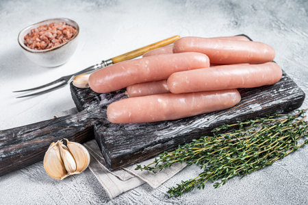 Chicken and turkey meat raw sausages on a wooden board with thyme. White background. Top viewの写真素材
