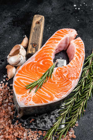 Raw Salmon trout Fish Steak on butcher table with meat cleaver. Black background. Top viewの写真素材