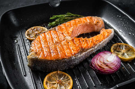 Salmon Fish Steak grilled on a grill pan with herbs. Black background. Top viewの写真素材