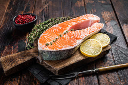 Fresh Raw Salmon trout Fish Steaks on wooden board with thyme and lemon. Wooden background. Top viewの写真素材