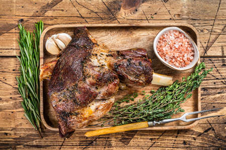 Roasted goat leg meat on a wooden cutting tray. wooden background. Top viewの写真素材
