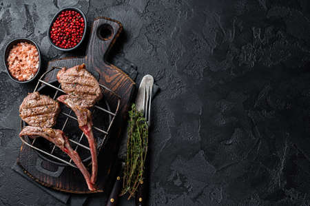 Grilled lamb mutton meat chops steaks on a grill. Black background. Top view. Copy spaceの写真素材