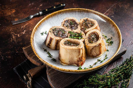 Baked marrow veal beef bones in plate with thyme and herbs. Dark background. Top viewの写真素材