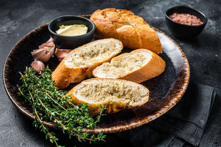 Garlic Spread on Toasted Baguette with Salt, Pepper, Thyme and Olive Oil in plate. Black background. Top viewの写真素材