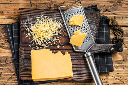 Grated cheddar cheese piece on a wooden board. Wooden background. Top viewの写真素材