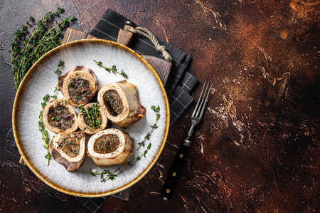 Baked marrow veal beef bones in plate with thyme and herbs. Dark background. Top view. Copy spaceの写真素材