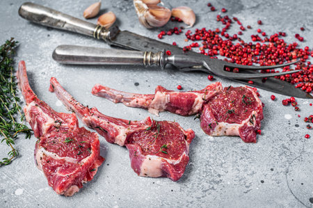 Uncooked lamb meat chops steaks on a butcher table with pepper and thyme. Gray background. Top viewの写真素材