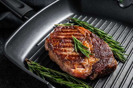 Roasted rib eye steak, ribeye beef meat in a grill pan. Black background. top view. Copy spaceの写真素材