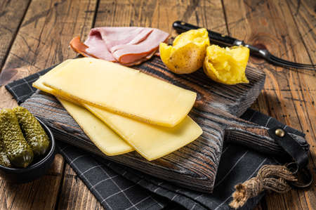 Ready for cooking Raclette Swiss cheese slices with boiled potato and ham. Wooden background. Top viewの写真素材