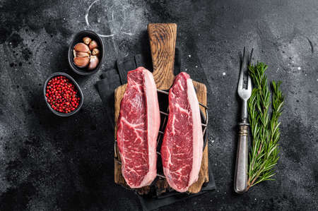 Raw top sirloin beef meat steak or brazilian Picanha on grill. Black background. Top viewの写真素材