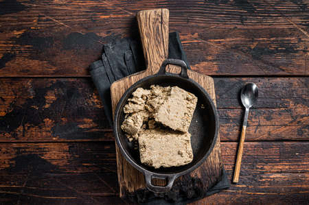 Halva with sunflower seeds and honey in pan. Wooden background. Top view