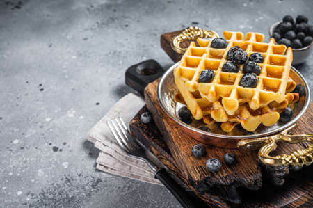 Fresh Belgian waffles with blueberry and Syrup in skillet. Gray background. Top view. Copy spaceの写真素材