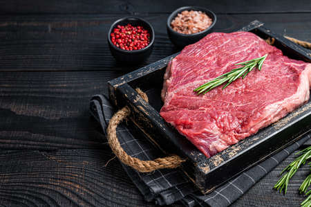 Beef raw fillet for steaks in a wooden tray with herbs. Black wooden background. Top view. Copy spaceの写真素材
