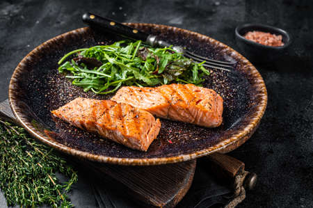 BBQ vegetarian dinner - grilled salmon fillets steaks on plate with salad. Black background. Top viewの写真素材