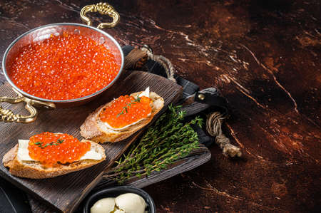 Delicious Sandwiches with fish Red caviar on wooden board. Dark background. Top view. Copy spaceの写真素材