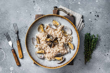 Italian Risotto with clams in a rustic plate with herbs. Gray backgroud. Top viewの写真素材