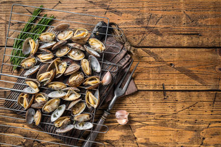 Cooked shells Clams, vongole on a grill with garlic and rosemary. Wooden background. Top view. Copy spaceの写真素材