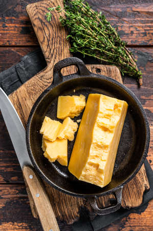 Parmesan hard cheese piece in a pan. Dark Wooden background. Top viewの写真素材