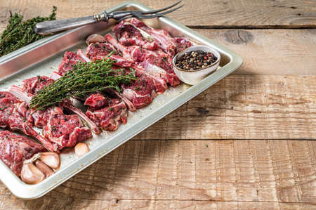 Raw uncooked lamb mutton meat chops steaks with thyme and garlic. Wooden background. Top view. Copy...