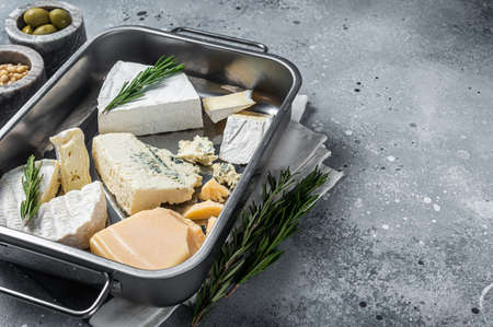 Different sorts of cheese - camembert, brie, blue cheese, parmesan with olives, nuts and herbs. Gray background. Top view. Copy spaceの写真素材