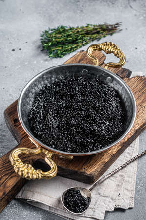 Luxury skillet with Black caviar on wooden board. Gray background. Top viewの写真素材